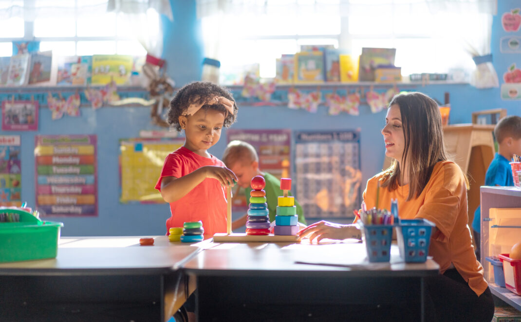 A preschool girl is actively learning and growing under the guidance of her teacher in a nurturing daycare environment